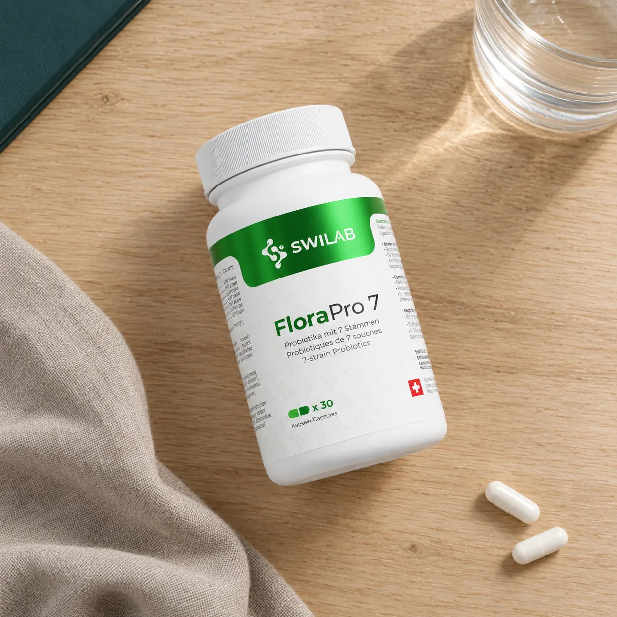 Avis clients sur le probiotique FloraPro 7 SwiLab : boîte de 30 gélules sur une table en bois, avec deux gélules et un verre d'eau.