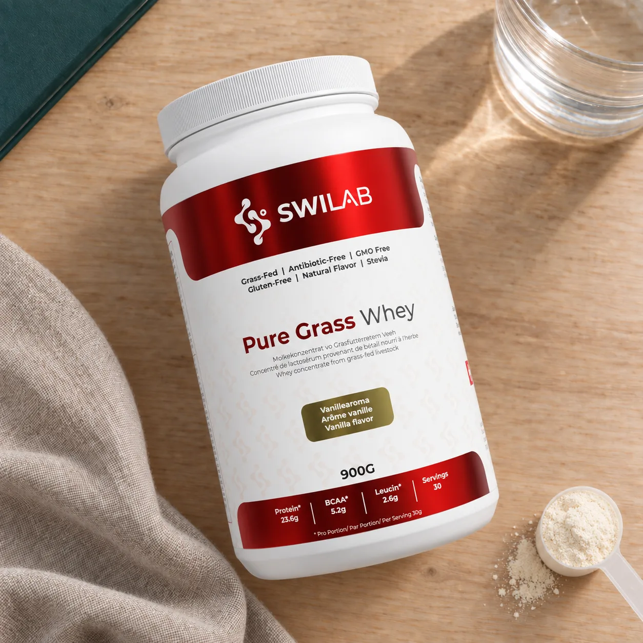 Barattolo di whey protein Pure Grass Whey SwiLab su un tavolo di legno, accanto a un bicchiere d'acqua e a un misurino di polvere.